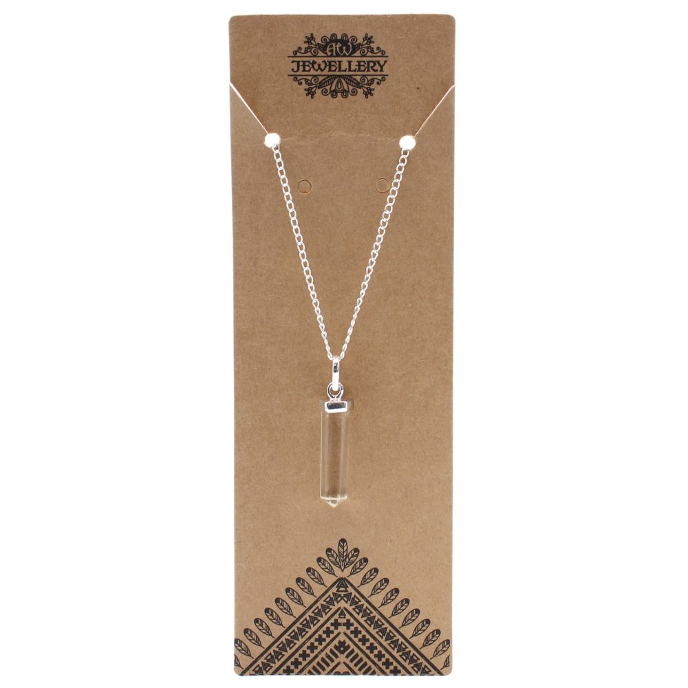 A necklace hangs against a brown display card. The chain is silver and holds a clear, crystal-like pendant. The card reads "JEWELLERY" and has a triangular pattern at the bottom.