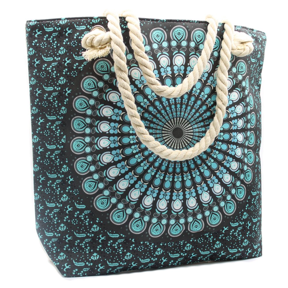 A tote bag stands, featuring a turquoise and white mandala pattern on a black background, with thick rope handles. The bag is positioned against a white backdrop.
