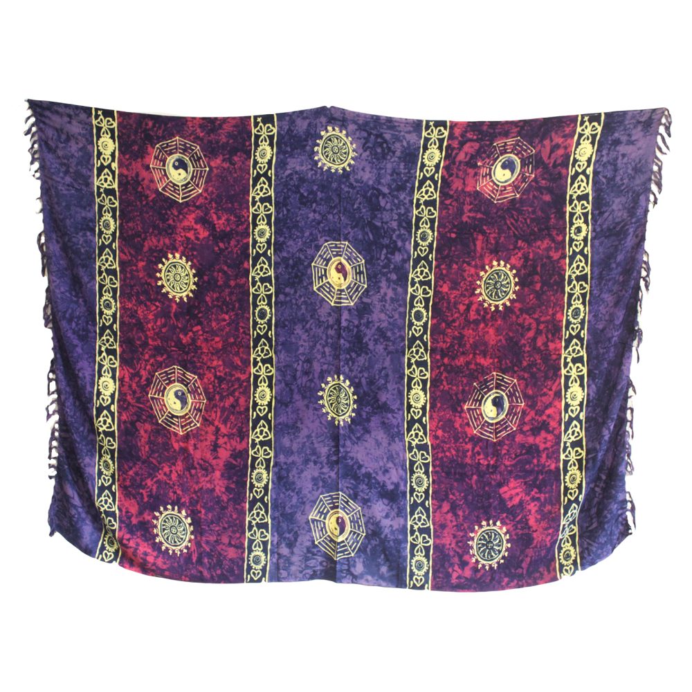 A rayon sarong hangs against a white background. It displays a batik pattern of purple and red with gold symbols.  The symbols are suns and Yin-Yang within hexagons.