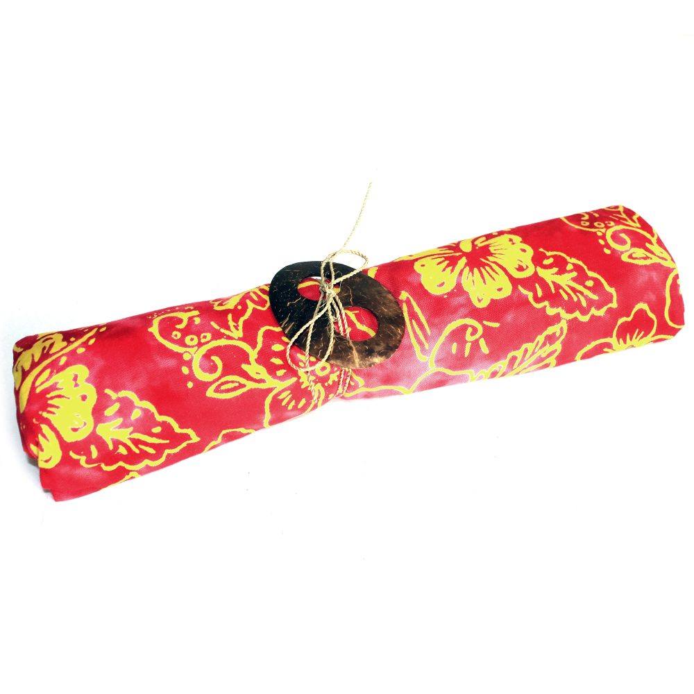 A red and yellow patterned fabric is rolled and tied with a coconut shell on a white background.