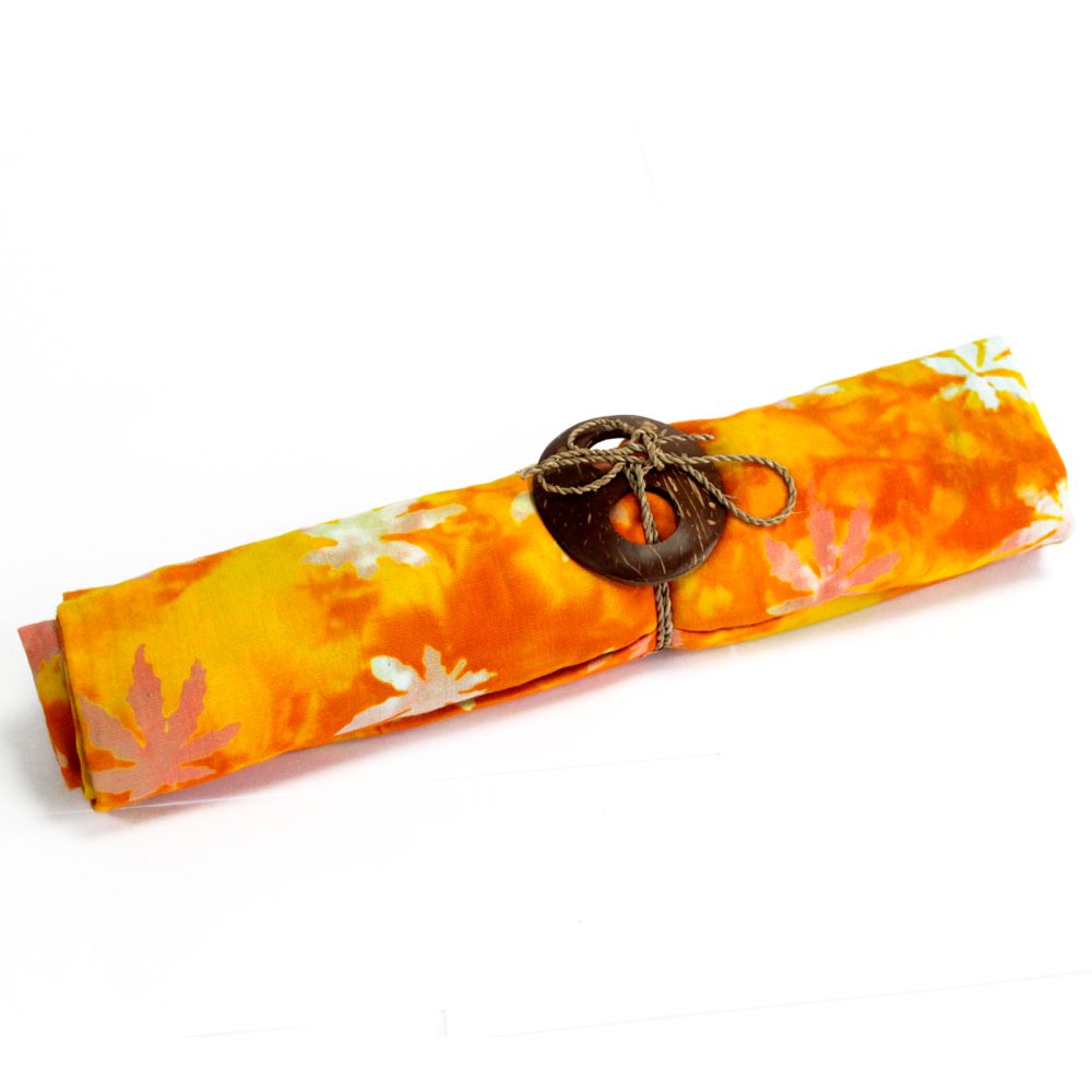 An orange fabric, featuring a batik-style leaf pattern, is rolled and tied with twine and a coconut shell button.  The roll rests on a white surface.