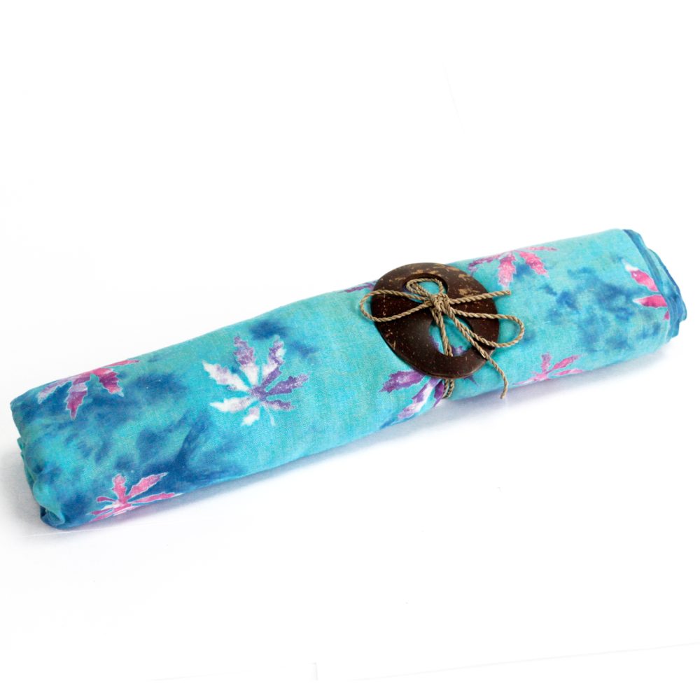 A teal fabric, patterned with pink and purple stylized flowers, is rolled and tied with twine and a coconut shell button.  It rests on a white background.