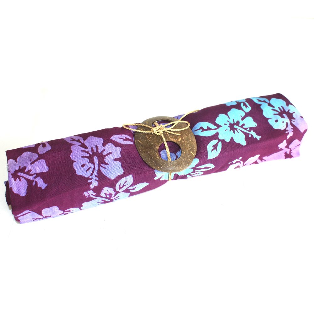 A purple fabric, patterned with light blue hibiscus flowers, is rolled and tied with twine and a coconut shell fastener on a white background.