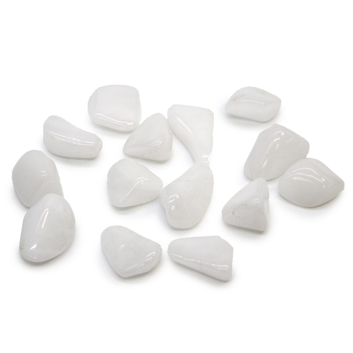 Several translucent white stones are arranged on a white surface. The stones vary in shape and size, exhibiting smooth, rounded edges and a polished appearance.