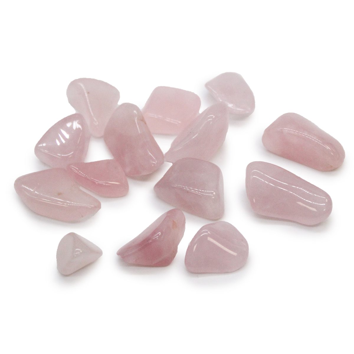 A scattering of polished, light pink rose quartz stones lies on a white surface. The stones have rounded edges and vary in size and shape.