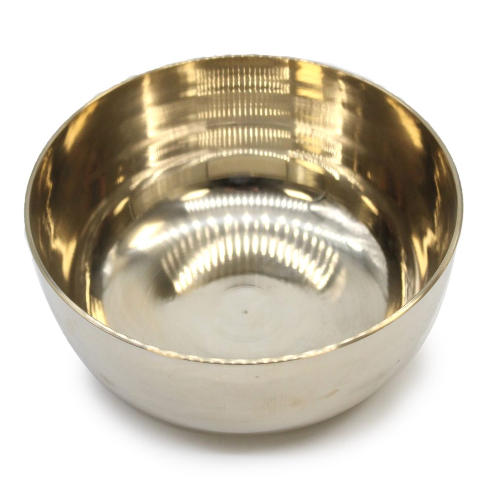 A shiny, metallic bowl is resting upright. It has a reflective surface with a golden hue on the inside, placed against a plain white background.