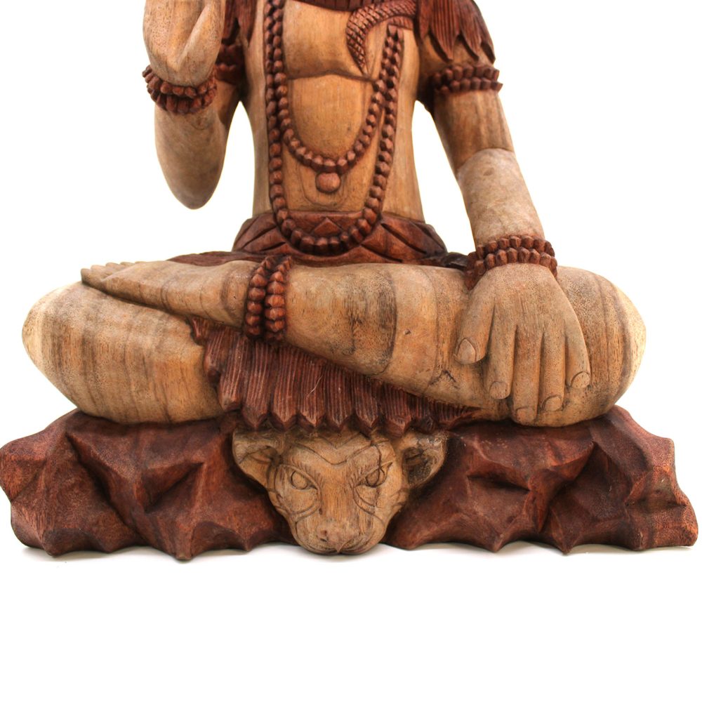 Wooden sculpture of a seated figure with crossed legs, adorned with beads, resting hands in lap. Positioned on a carved animal-faced base, suggesting a serene, meditative context.