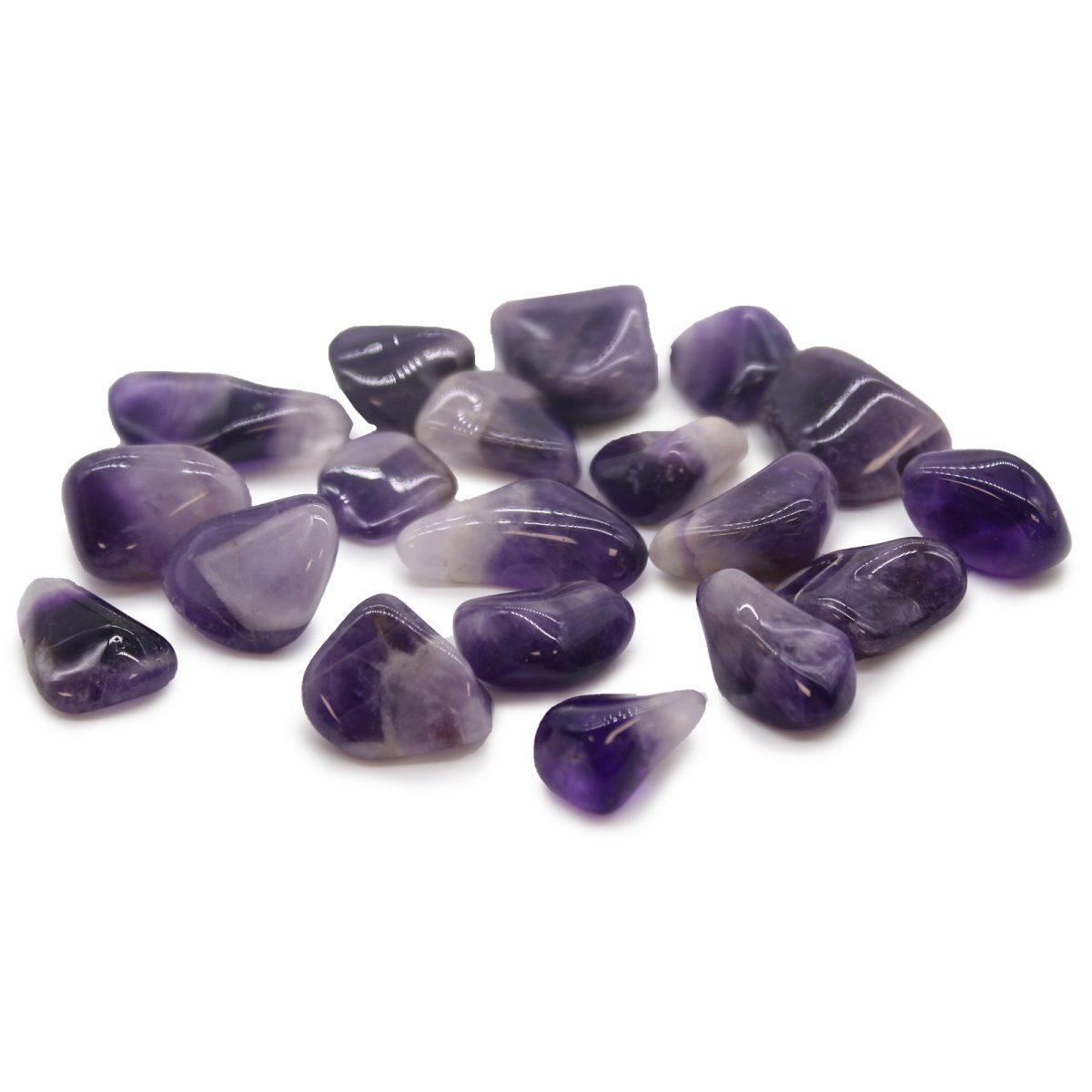 A collection of amethyst gemstones scatters across a plain white surface, displaying a variety of shapes, sizes, and purple shades.