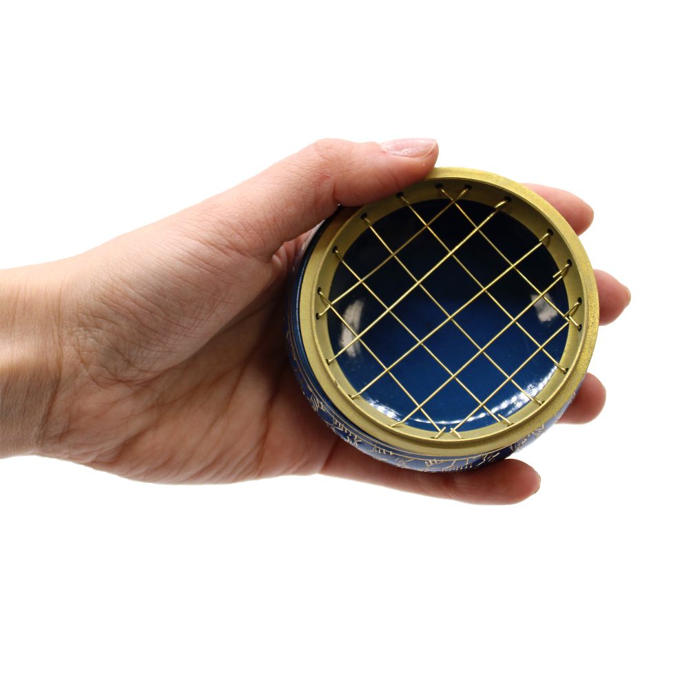 A hand holds a round blue tin with a gold grid on top, suggesting a lid. The background is plain white, focusing on the tin's structure.