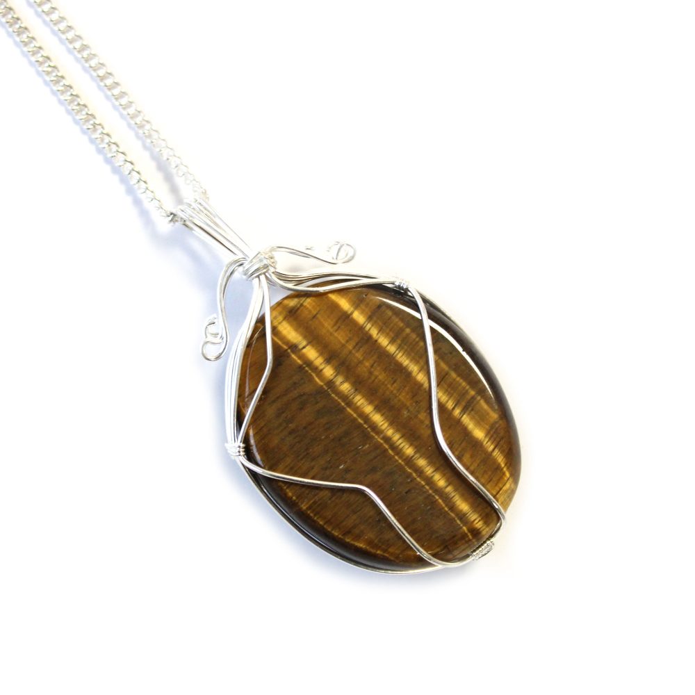 A brown, striped tiger's eye stone is wrapped in silver wire, forming a pendant. The pendant hangs from a silver chain against a white background.