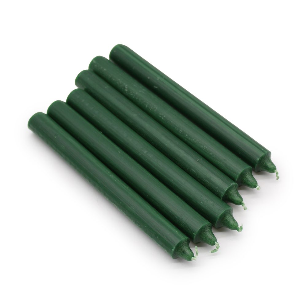 Six green candles sit parallel and angled on a white surface. The candles are long, thin, and cylindrical.