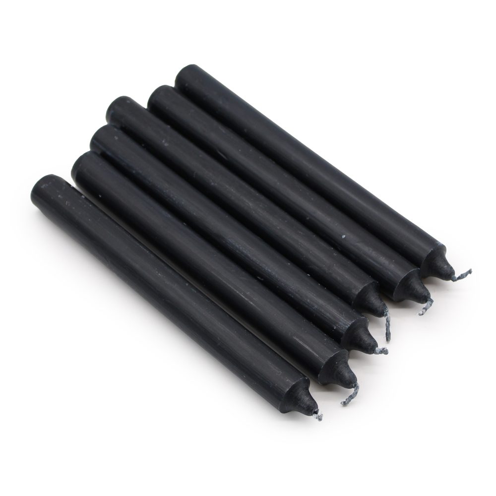Six dark-grey, thin candles are arranged side-by-side on a plain white surface. The candles taper slightly toward the top where the wicks are visible.