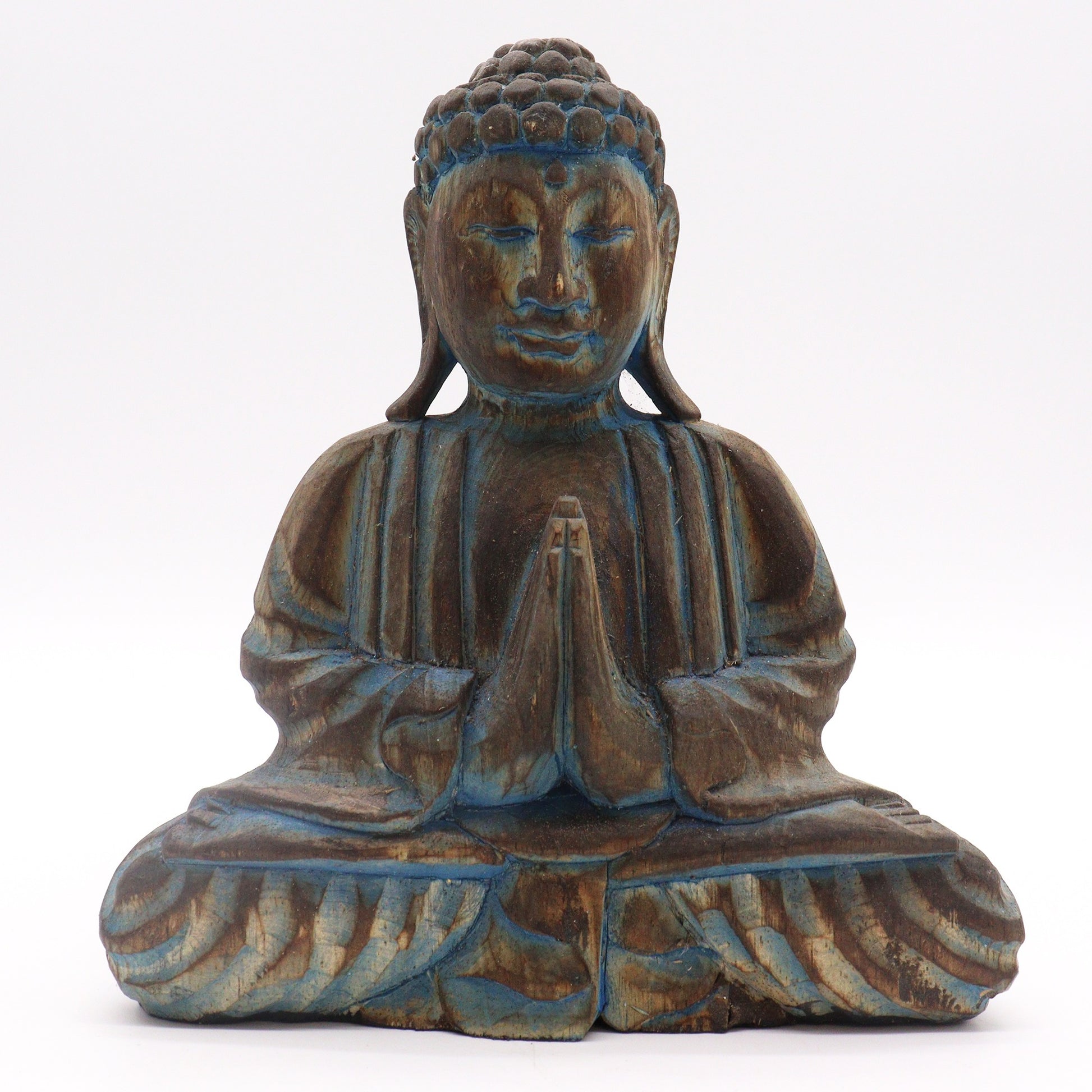 Wooden Buddha statue sits cross-legged with hands in a prayer position, adorned with a serene expression and intricate carvings, set against a plain white background.