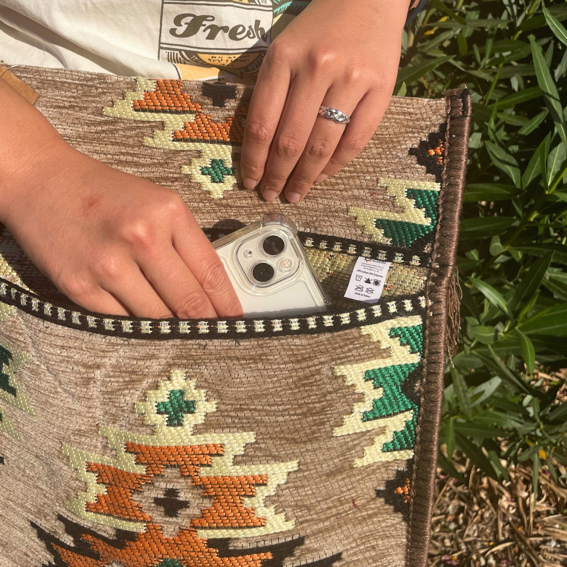 Hands place a phone in the pocket of a patterned bag, outdoors.
Text:
Fresh
BOTTLE
WISDOM.
Imported by ADAK LTD. UK
All Artisan 5.1. ES
50% Cotton 50% Polyester
Made in Turkey