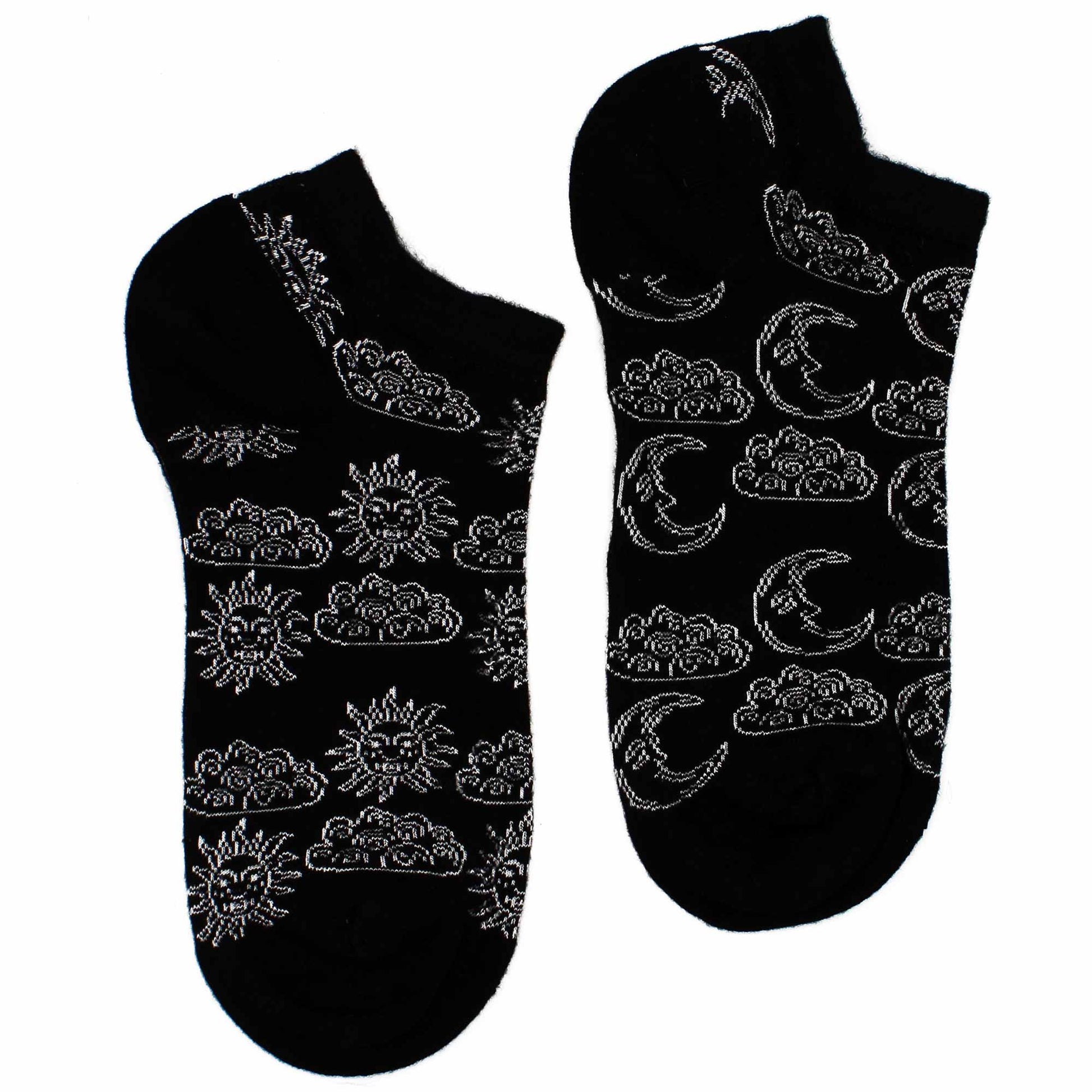 A pair of black ankle socks displays a pattern of suns, moons, and clouds,  is shown against a white background.