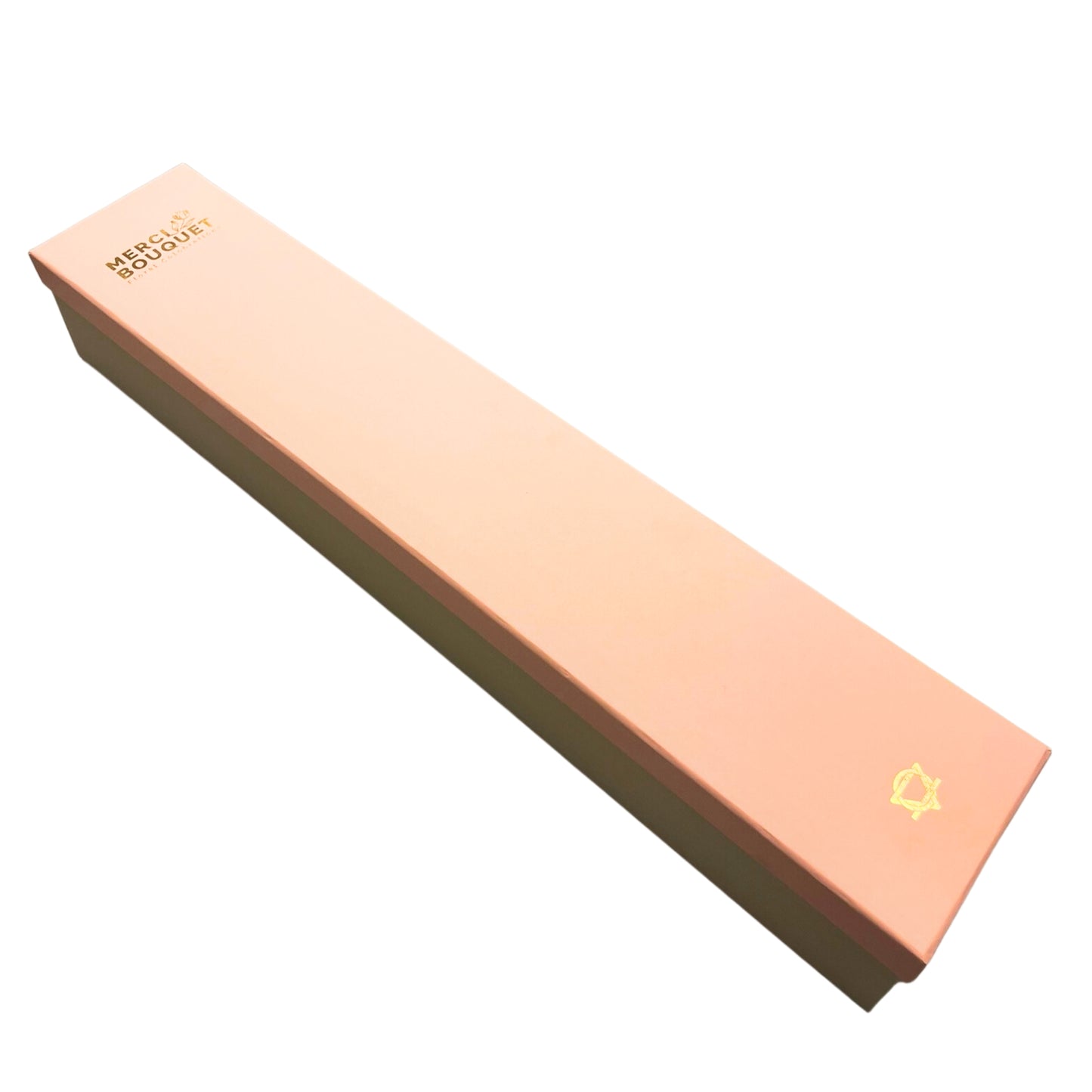 A long, rectangular box rests on a white background.  It is peach-colored with a darker base and features gold lettering: "MERCI BOUQUET  Floral Designers".