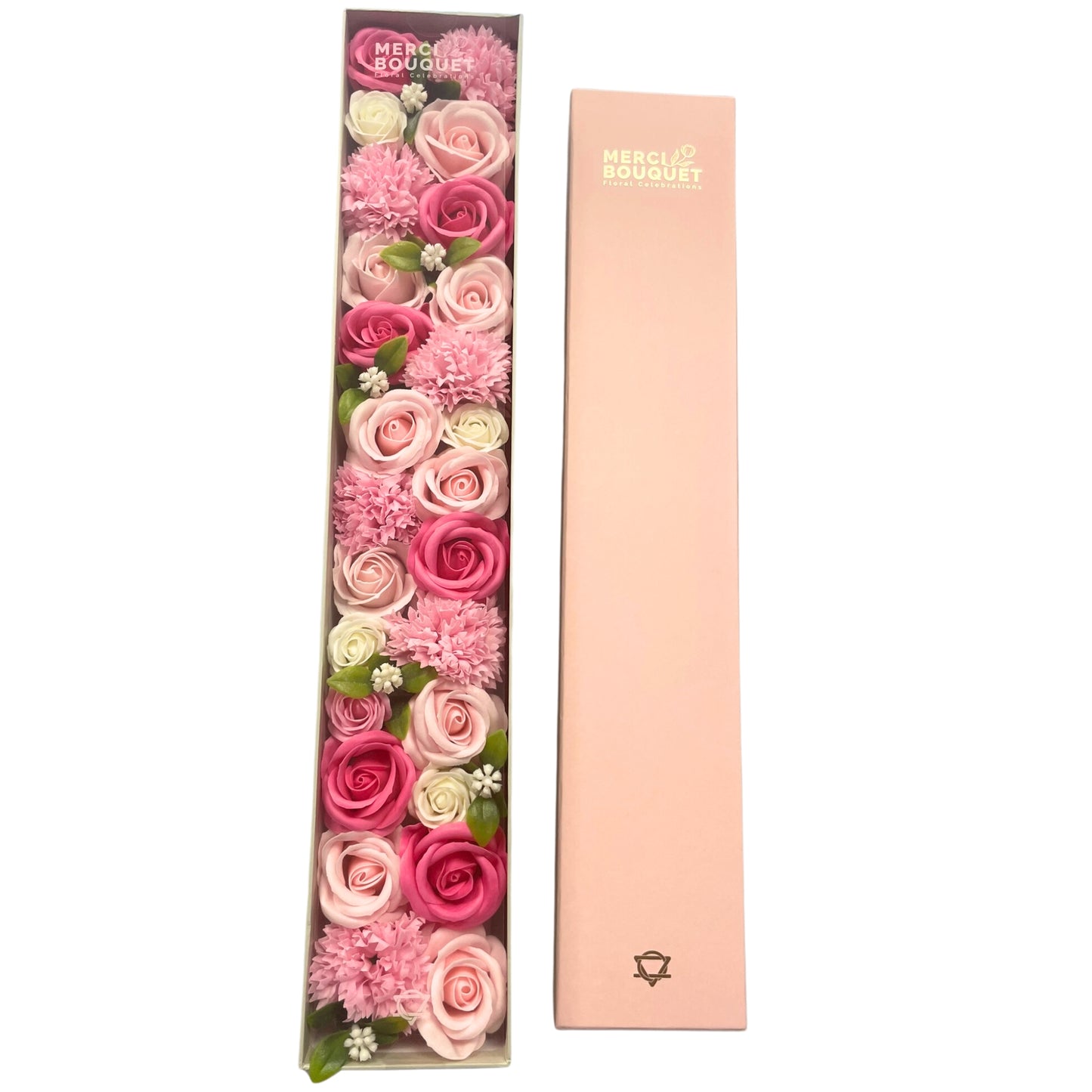 A long box containing a pink and white soap flower arrangement sits next to its matching lid.  MERCI BOUQUET Floral Celebrations is printed on both the box and its lid.