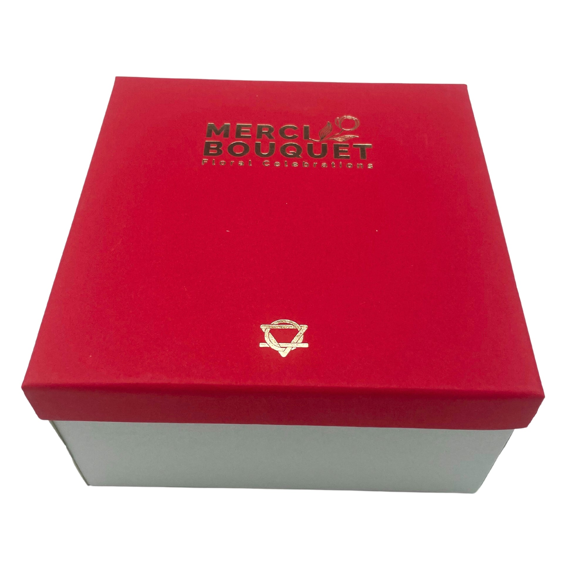 A red box with a gold logo sits on a white background. The logo reads "MERCI BOUQUET Floral Celebrations".  A smaller gold symbol is below the text.