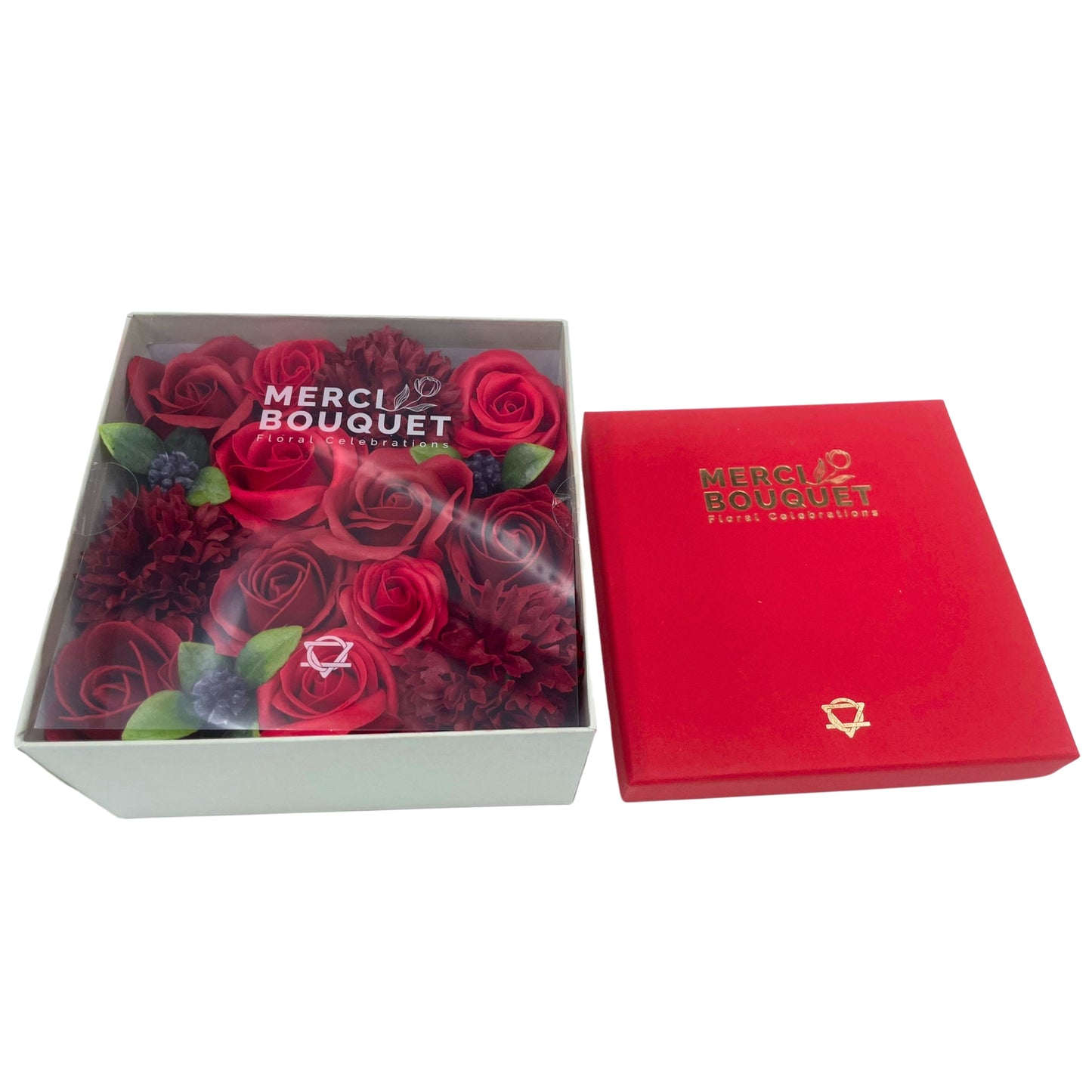 A red and burgundy soap flower arrangement is presented in a light green box.  The box is open, and a matching red box sits next to it.  Both boxes have the logo "MERCI BOUQUET Floral Celebrations" and a symbol.