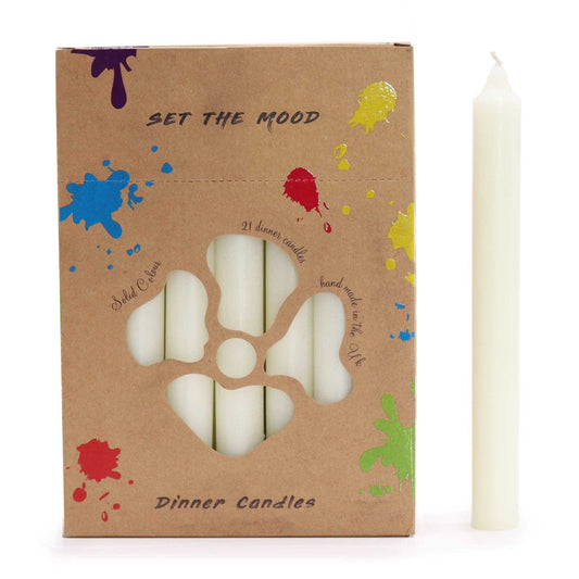 A box of white dinner candles, partially visible through a flower-shaped cutout, sits beside a single, loose candle. The box is decorated with colorful paint splatters and the text "SET THE MOOD", "21 dinner candles", "Solid Colour", "Dinner Candles", and "hand made in the Uk".