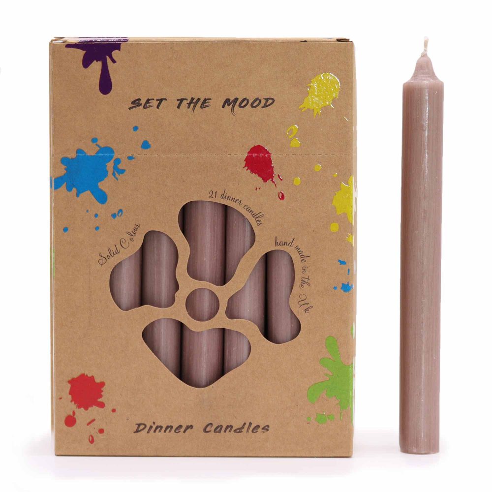 A box of taupe candles features a flower-shaped cutout showcasing the candles within. One candle stands beside the box. The box reads "SET THE MOOD," "Solid Colour," "21 dinner candles," "hand made in the UK," and "Dinner Candles". The box is decorated with bright paint splatters.