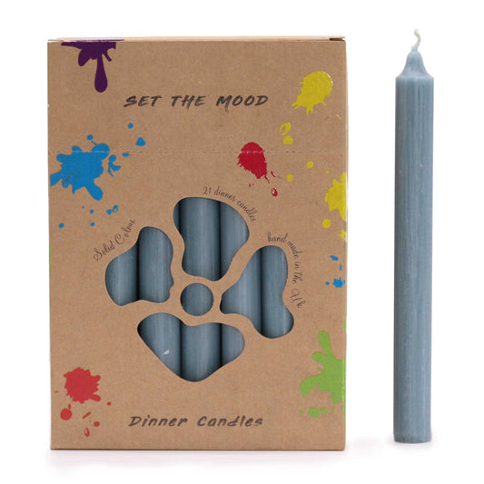 A cardboard box decorated with paint splatters holds blue candles behind a cut-out, next to a single, tall, blue candle. Text reads: "SET THE MOOD, Solid Colour, 21 dinner candles, hand made in the Uk, Dinner Candles".