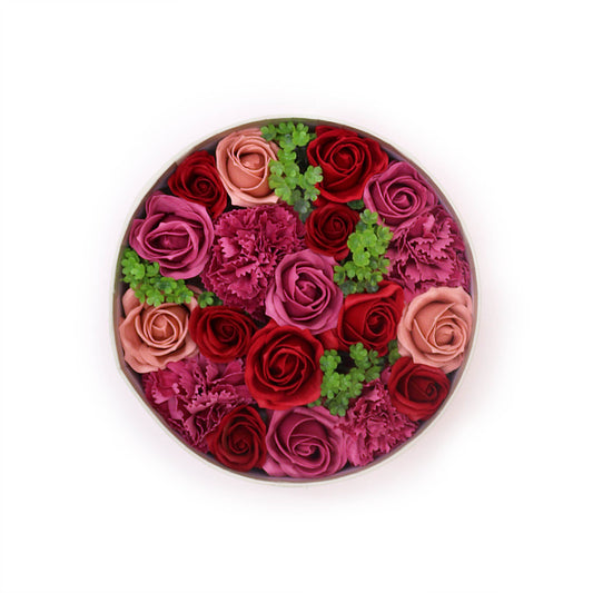 Roses and carnations, arranged in a circular box, are displayed against a white background.
