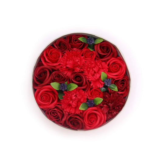 A circular arrangement of red roses and carnations sits in a light grey box, against a white background.