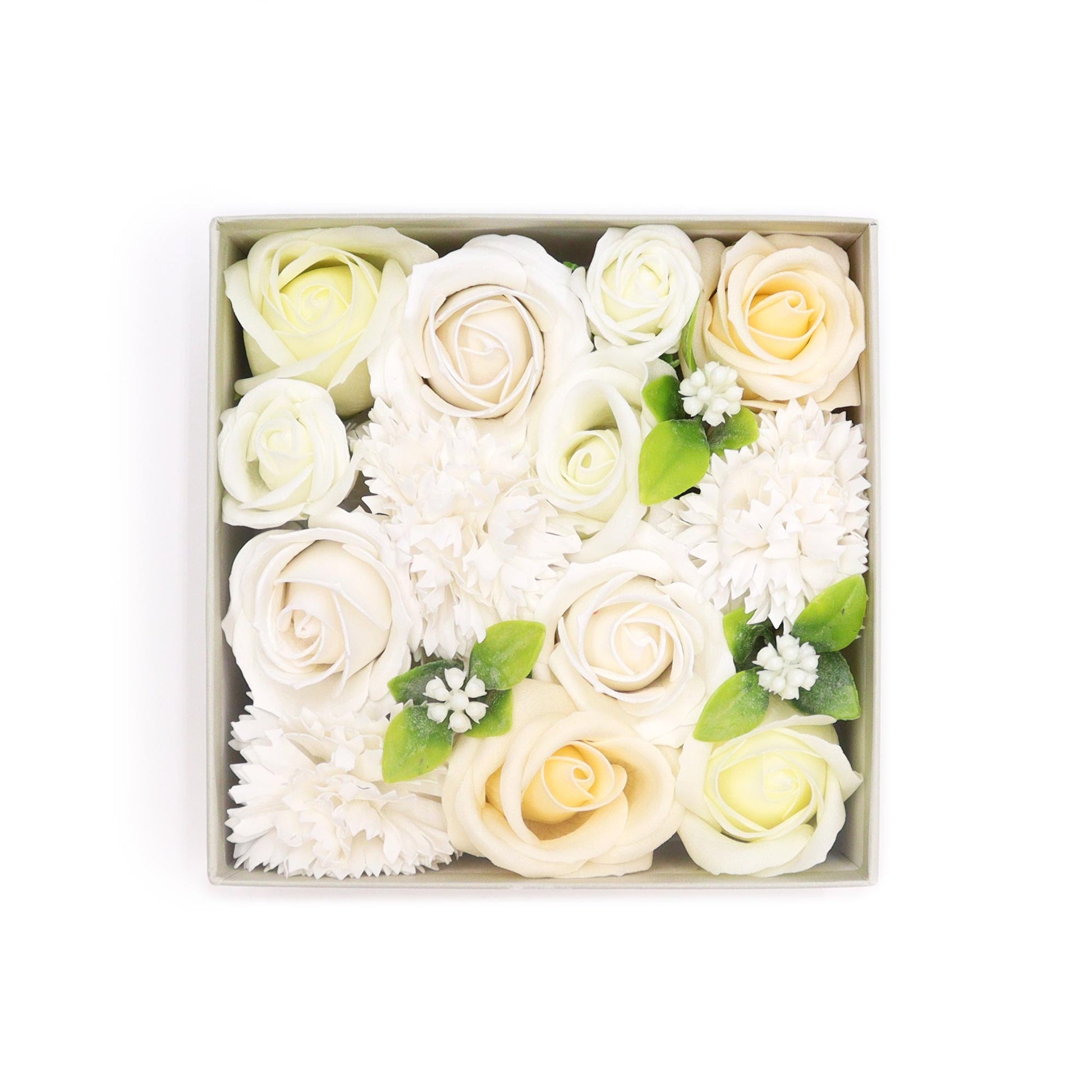 A square box contains an arrangement of cream and white roses and carnations.  The flowers are nestled together, creating a full, dense floral display.  The box is light beige, providing a neutral backdrop.