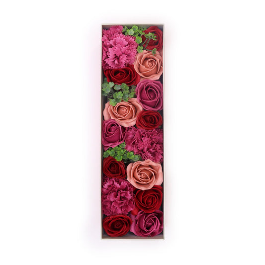 Roses and carnations of varying red and pink shades are arranged vertically in a rectangular box, creating a floral display against a white background.