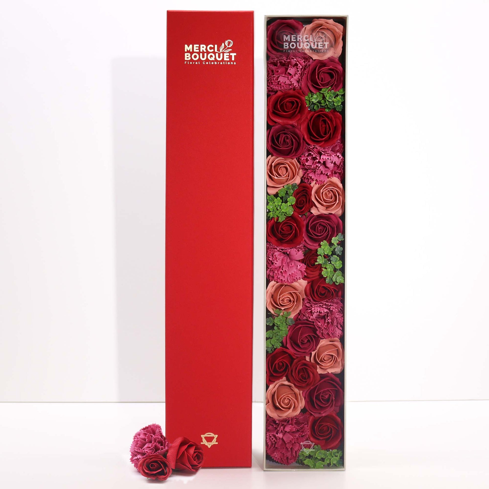 A tall box of red roses and carnations sits beside a matching empty box.  The flowers are arranged vertically.  The boxes are labeled "MERCI BOUQUET Floral Celebrations".