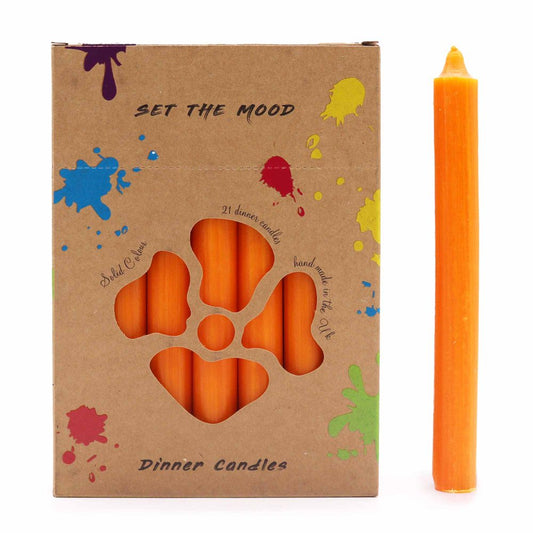 A box of orange dinner candles advertises "SET THE MOOD" with "21 dinner candles." One candle stands next to the box, which has colorful paint splatter designs and says "Solid Colour," "Hand made in the Uk," and "Dinner Candles."