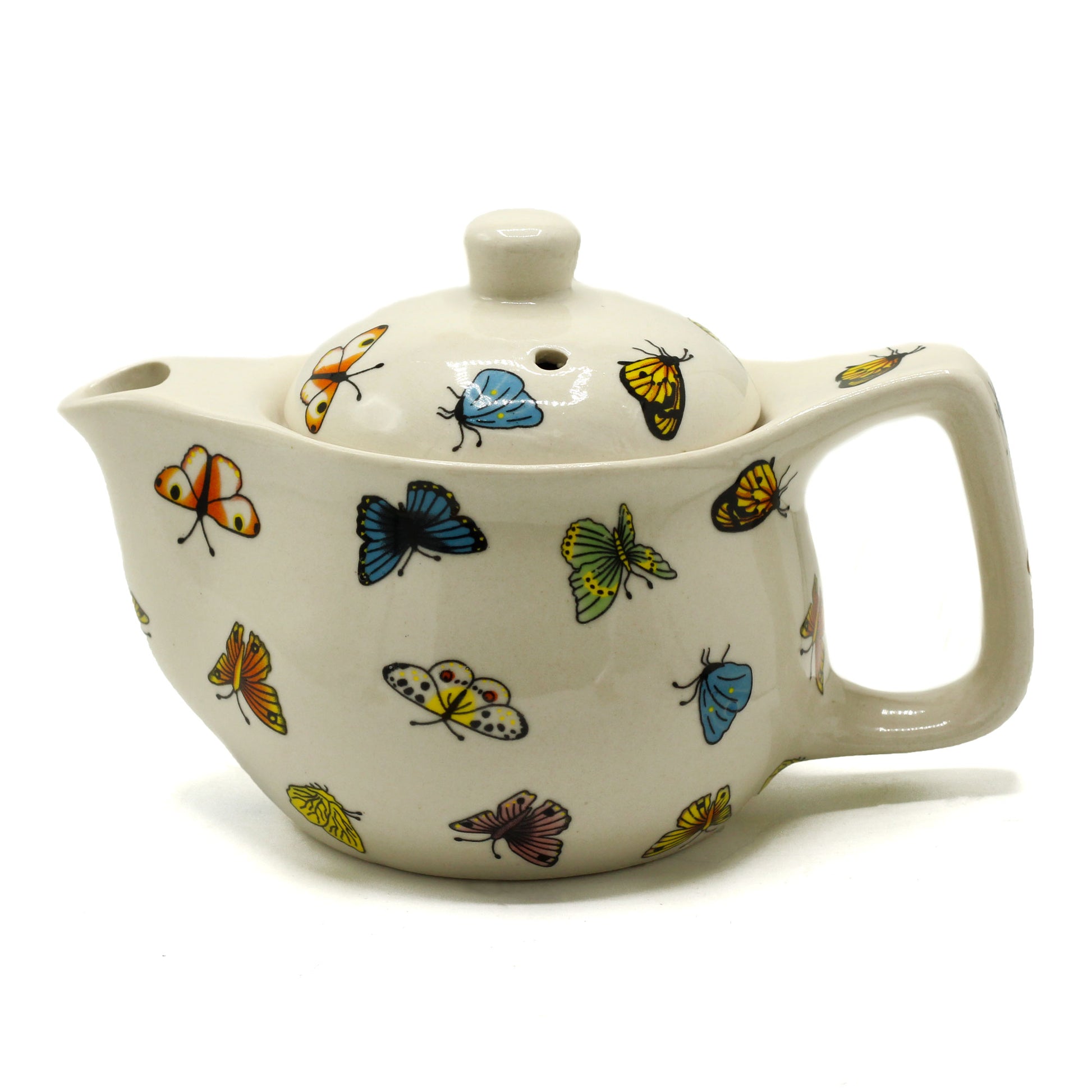 A ceramic teapot, adorned with colorful butterfly designs, sits on a white background.  The teapot has a curved body, a handle, and a lid with a small hole.