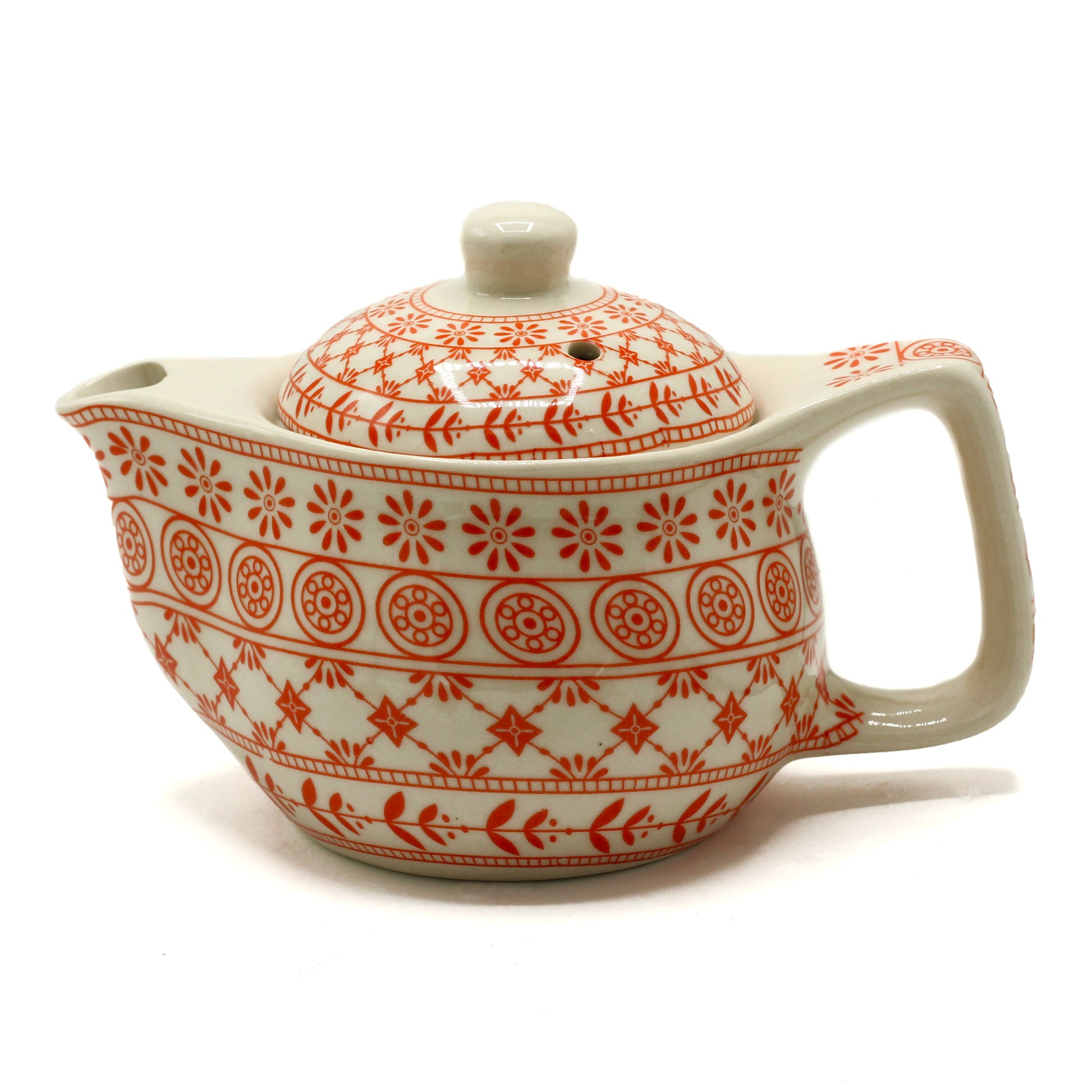 A ceramic teapot, adorned with an orange floral pattern, sits on a white background.