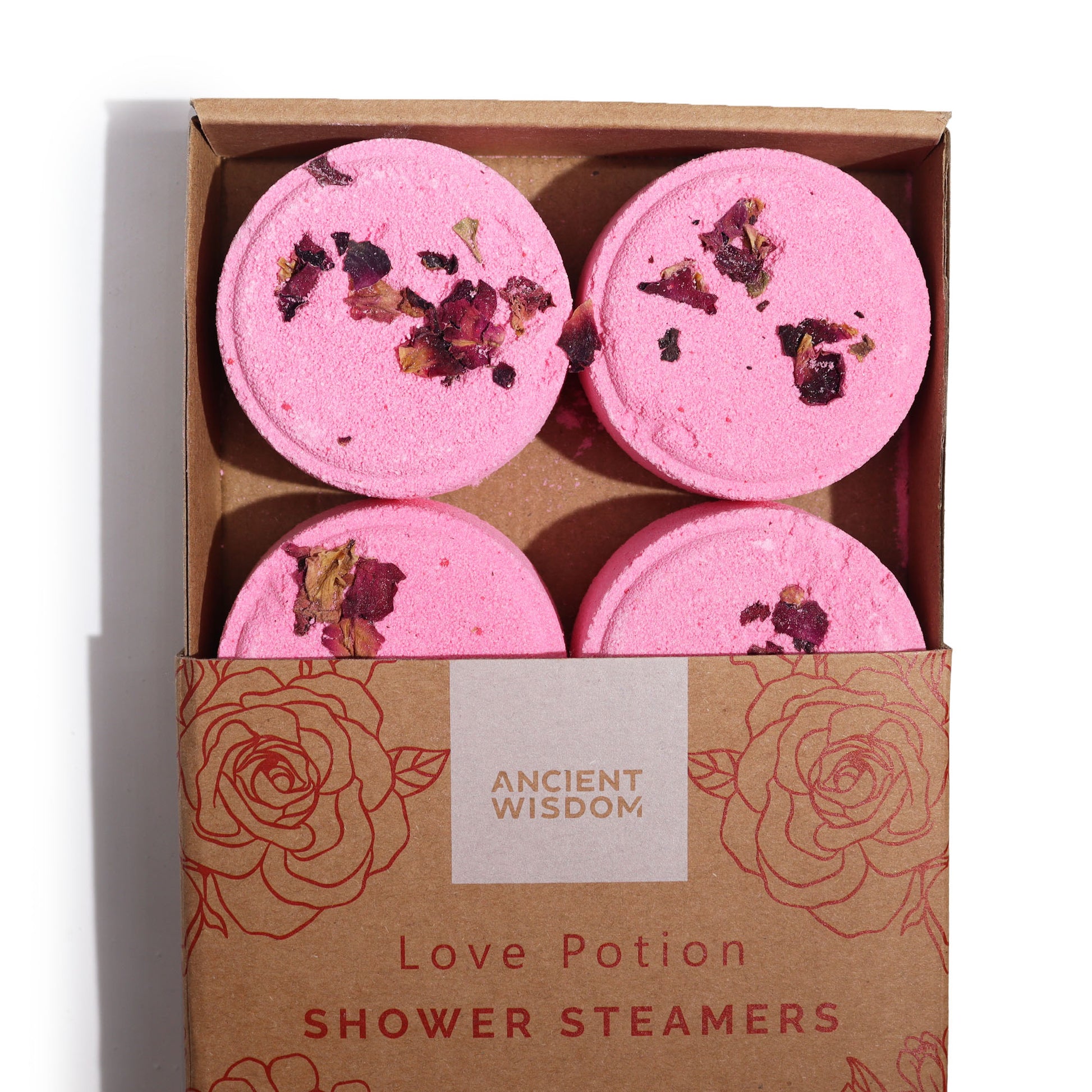 Four pink shower steamers with dried flower petals, arranged in a cardboard box with floral designs. The box reads: "ANCIENT WISDOM Love Potion SHOWER STEAMERS."