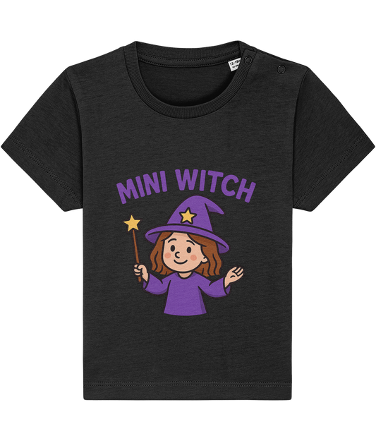 Black toddler t-shirt depicting a smiling cartoon girl in a purple witch hat and robe holding a star-tipped wand, centered on the chest; text above reads "MINI WITCH".