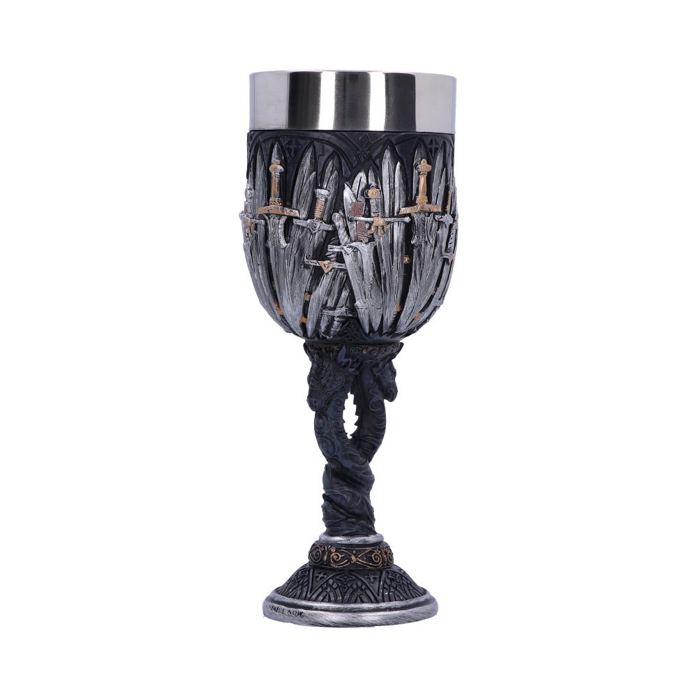 A metal goblet, with a silver rim, is intricately designed with detailed swords encircling the cup, and dragons twisting around its stem; it sits on a decorated base.