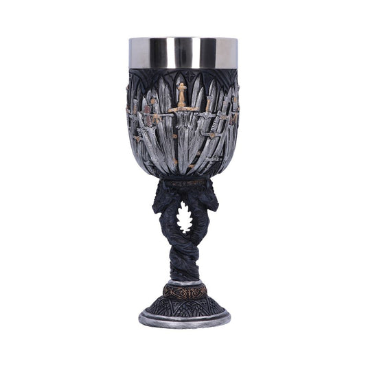 A goblet, detailed with interwoven swords, sits on a base with a decorative swirl, against a white background. The cup is silver and dark gray.