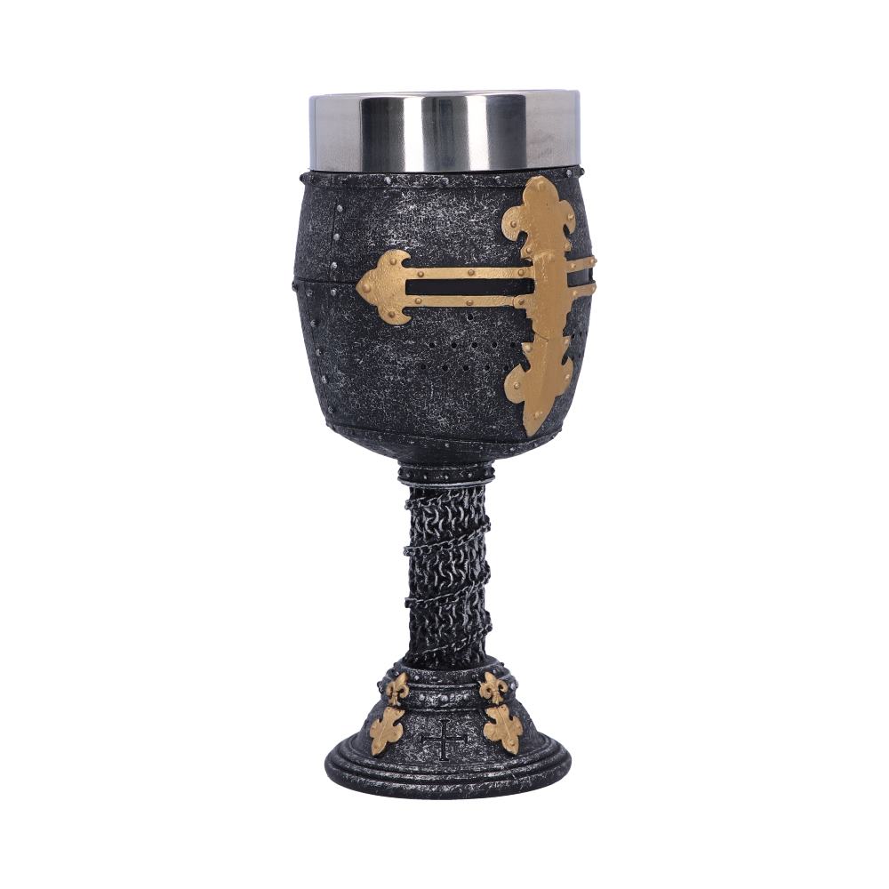 A metal goblet resembling a crusader helmet sits on a white surface. The cup section features a gold cross, and the stem is textured like chainmail.