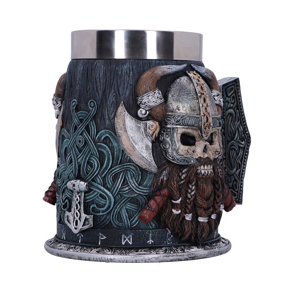 A metal-topped mug features a Viking skull with a horned helmet and beard. The mug is carved with Norse designs, including a shield and axe, and runes around the base.