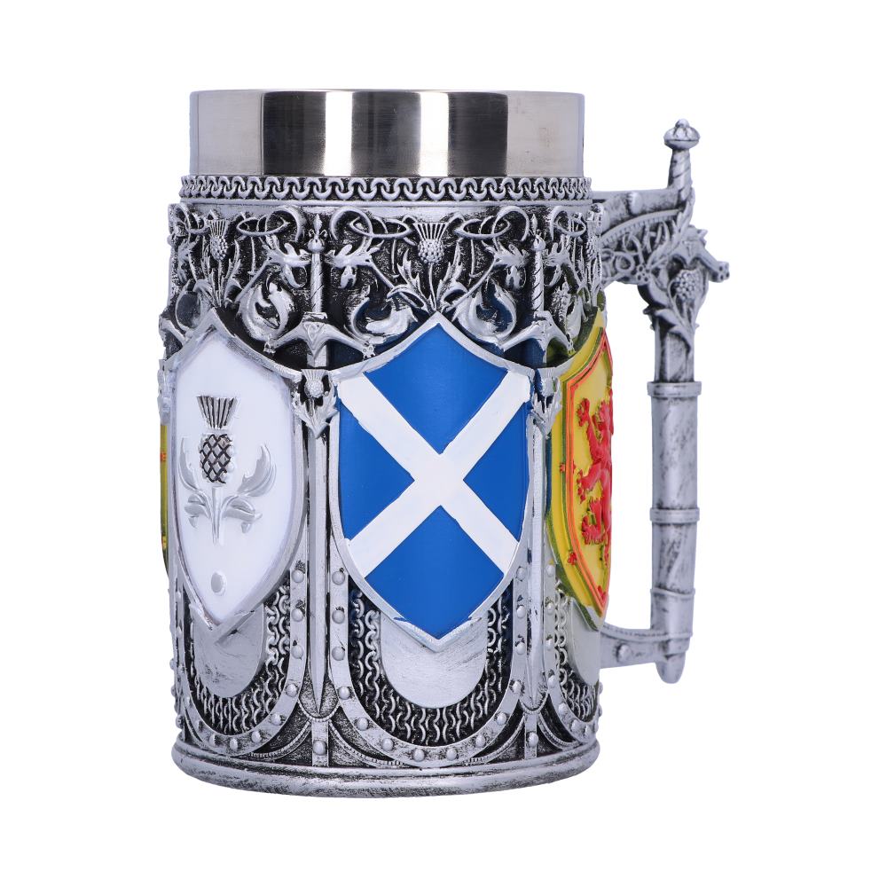 A decorative silver-colored mug stands, adorned with shields. The shields depict a thistle, the Scottish flag, and a lion rampant, set against a white background.