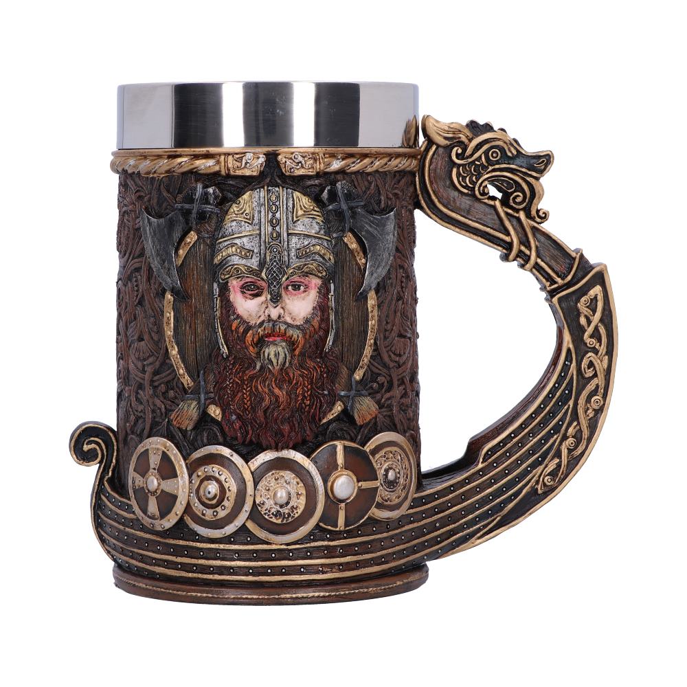 A metal and wood-like mug displays a Viking's face wearing a helmet, crossed axes behind him, with shields decorating the base and a dragon's head on the handle.