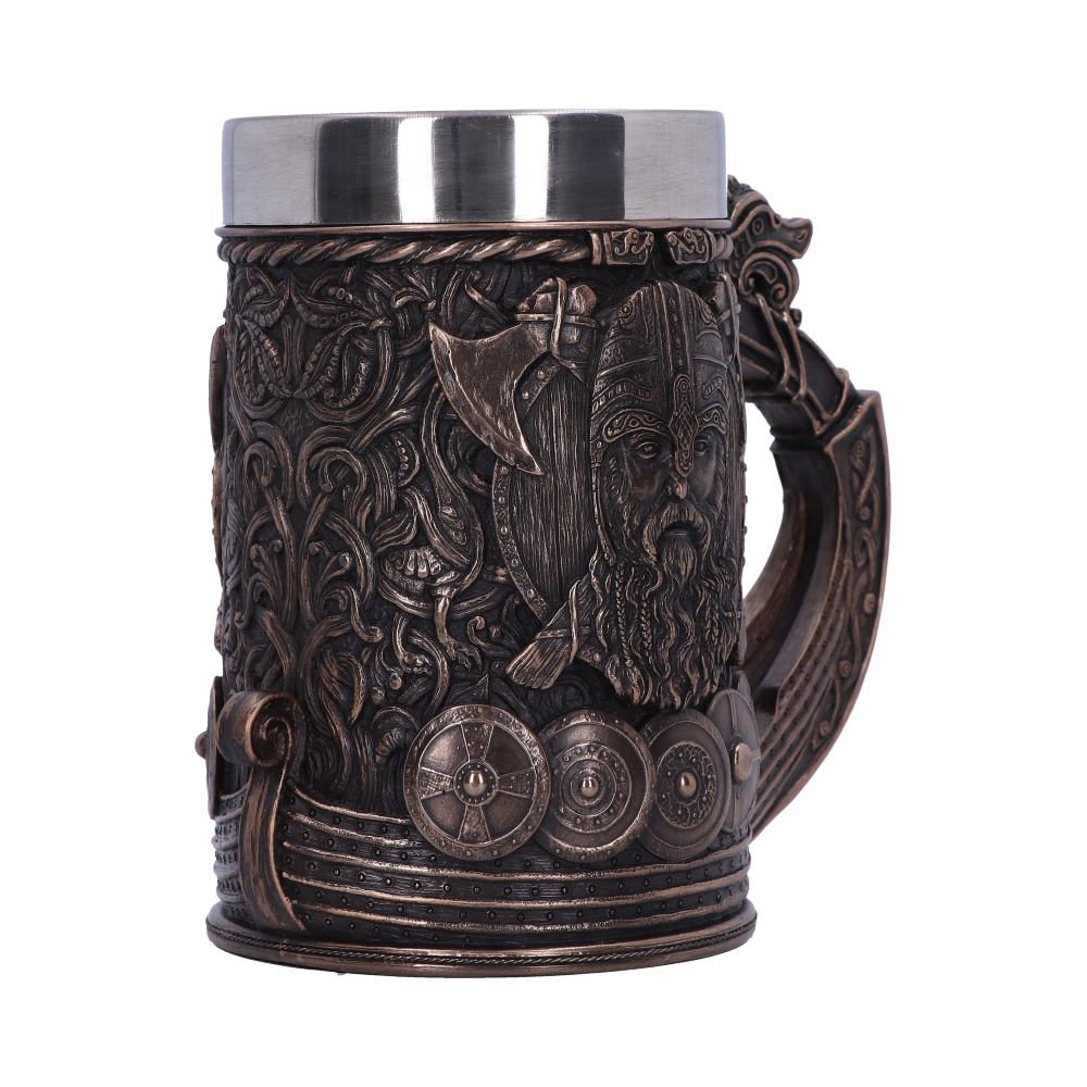 A large, bronze-colored mug is ornately decorated with Viking imagery, including a bearded face, axe, shields, and longboat, on a white background. The top is stainless steel.
