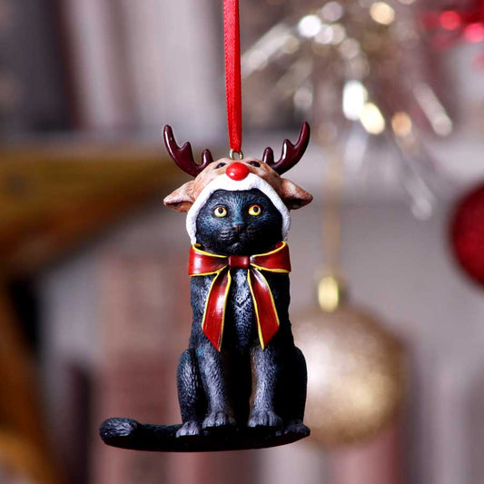 Black cat ornament wearing a reindeer hat and red bow hangs from a red ribbon against a blurred festive background of sparkling lights and round ornaments.