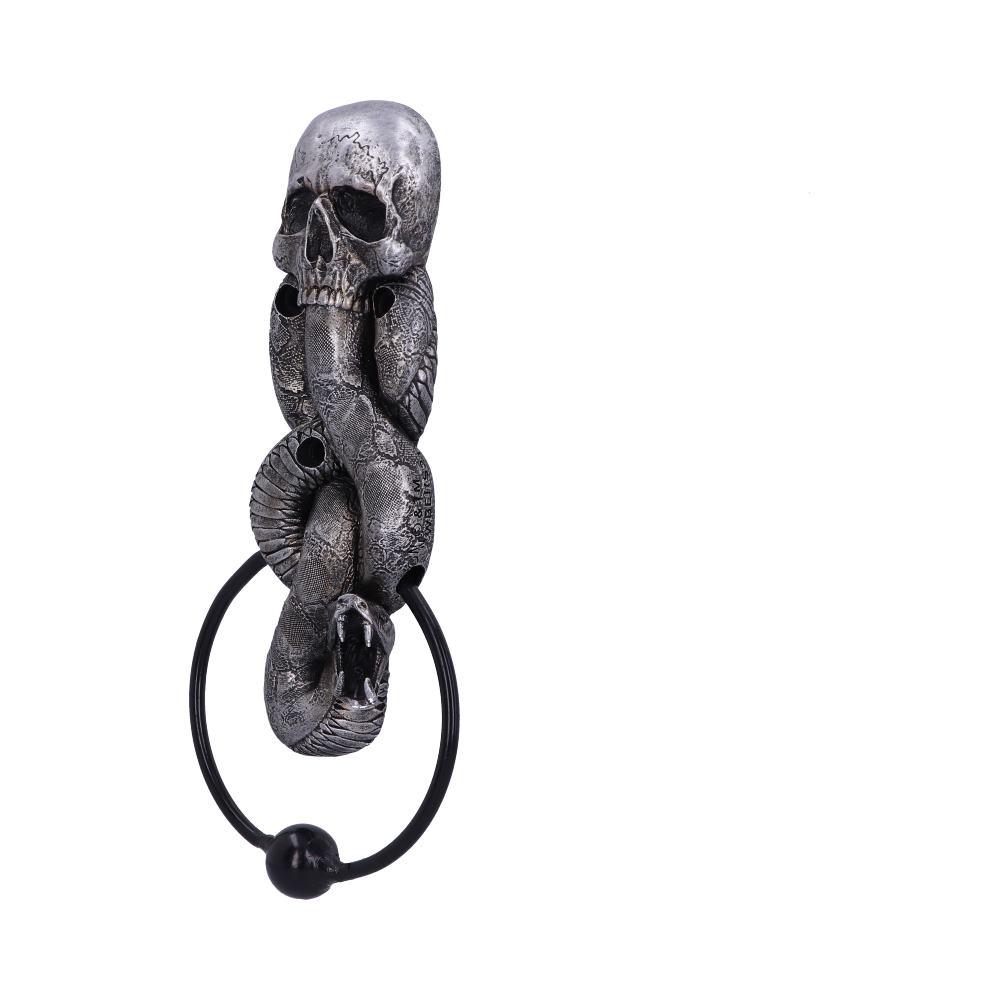 A metallic door knocker features an intricately detailed skull entwined with a coiled snake. The snake's open mouth holds a ring below, set against a plain white background.