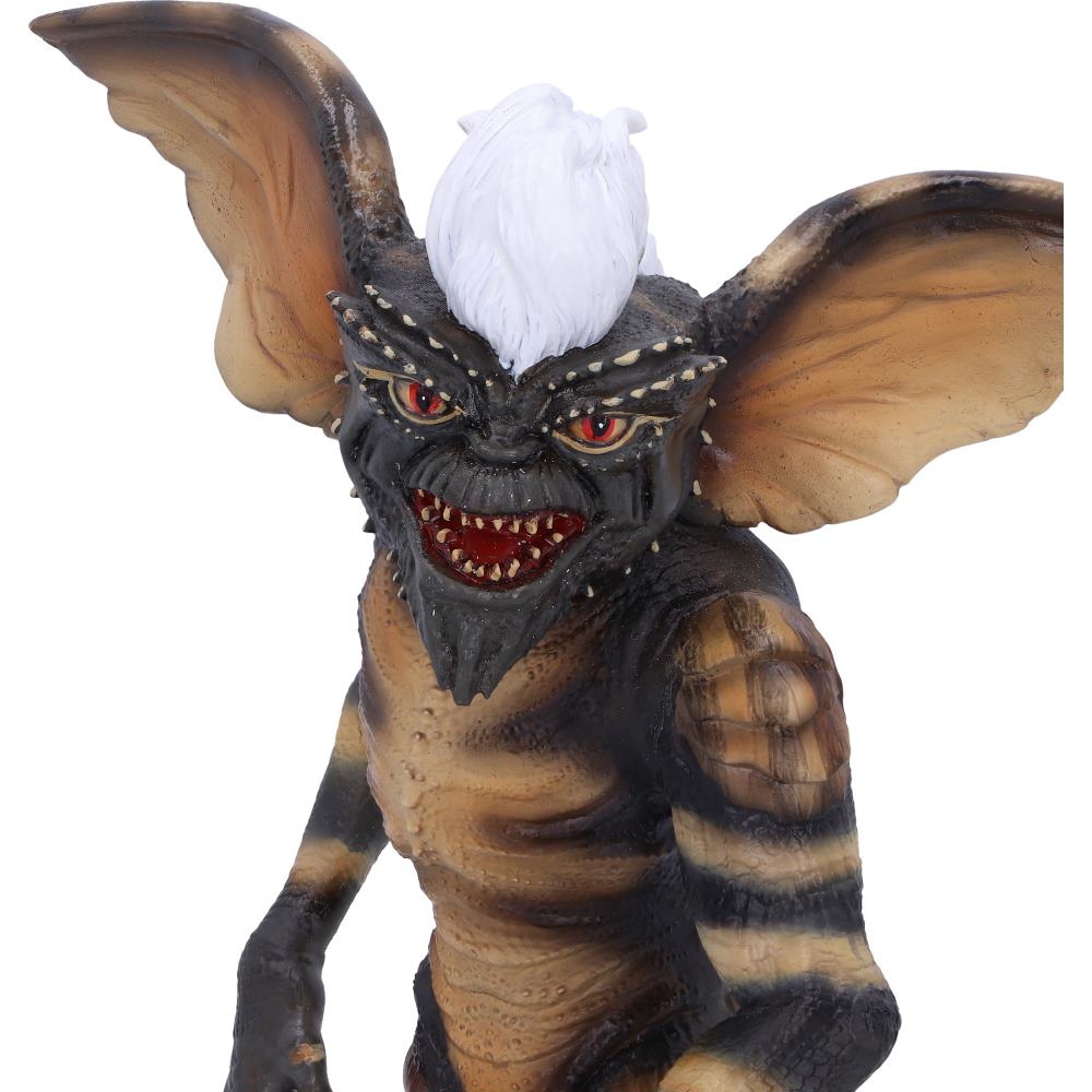 A creature figurine with bat-like ears, red eyes, sharp teeth, and a white mohawk stands aggressively, featuring a striped body pattern, against a plain white background.