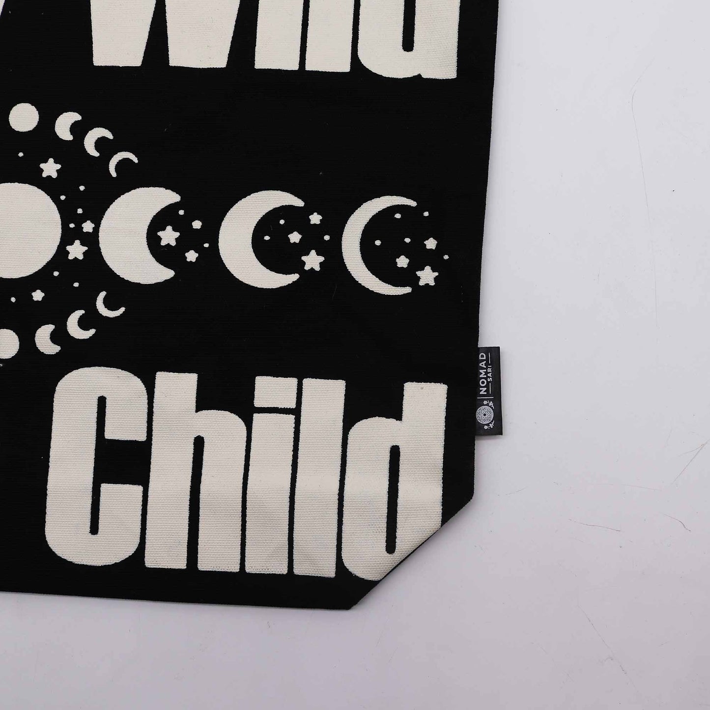 Stay Wild Moon Child black and natural 10oz cotton tote bag with moon phase design and button closure.