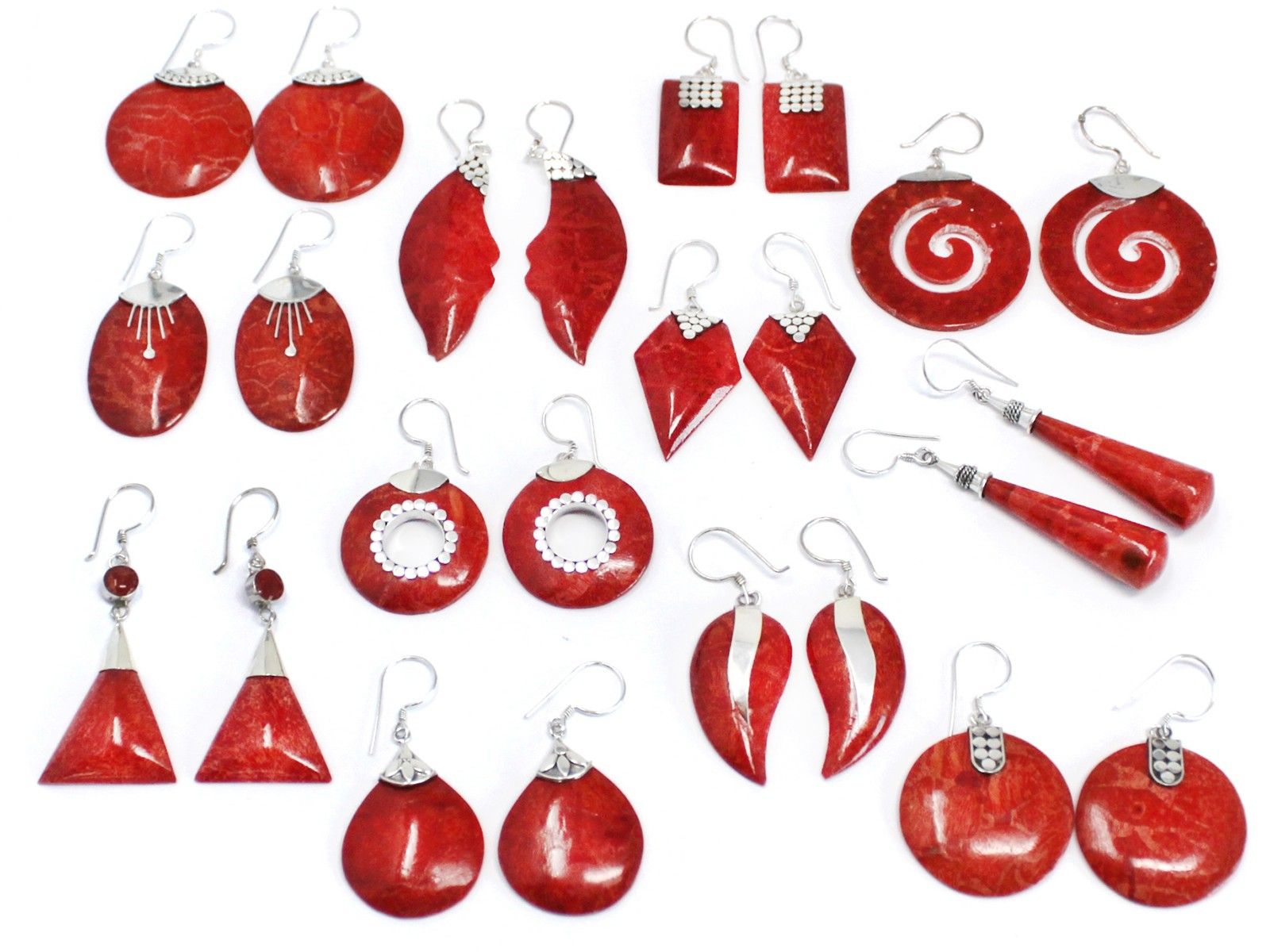 Red stone earrings form pairs displayed flat on a white surface, showing varied shapes, circles, teardrops, spirals, triangles, and silver hooks and accents arranged in rows.