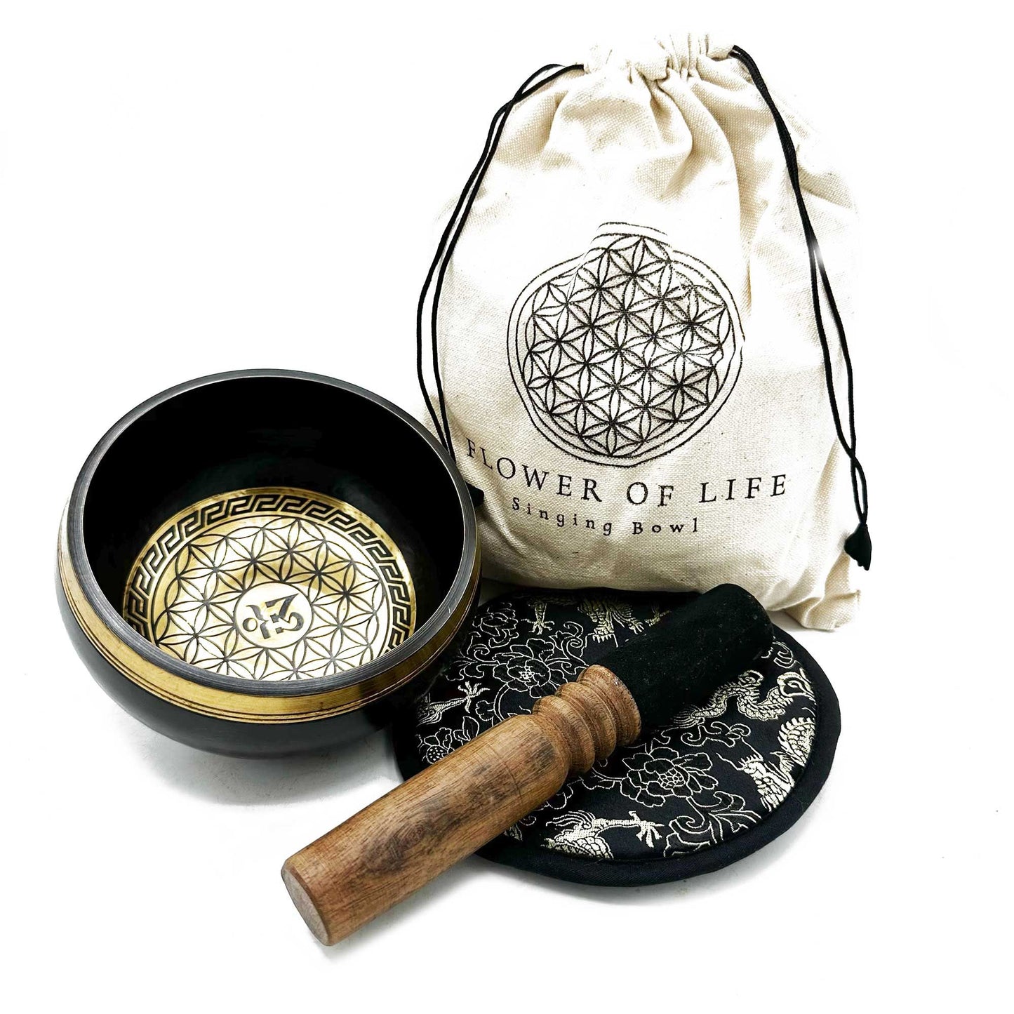 Singing bowl sits open beside a drawstring bag labeled FLOWER OF LIFE Singing Bowl and a wooden mallet resting on a patterned cushion on a white background.