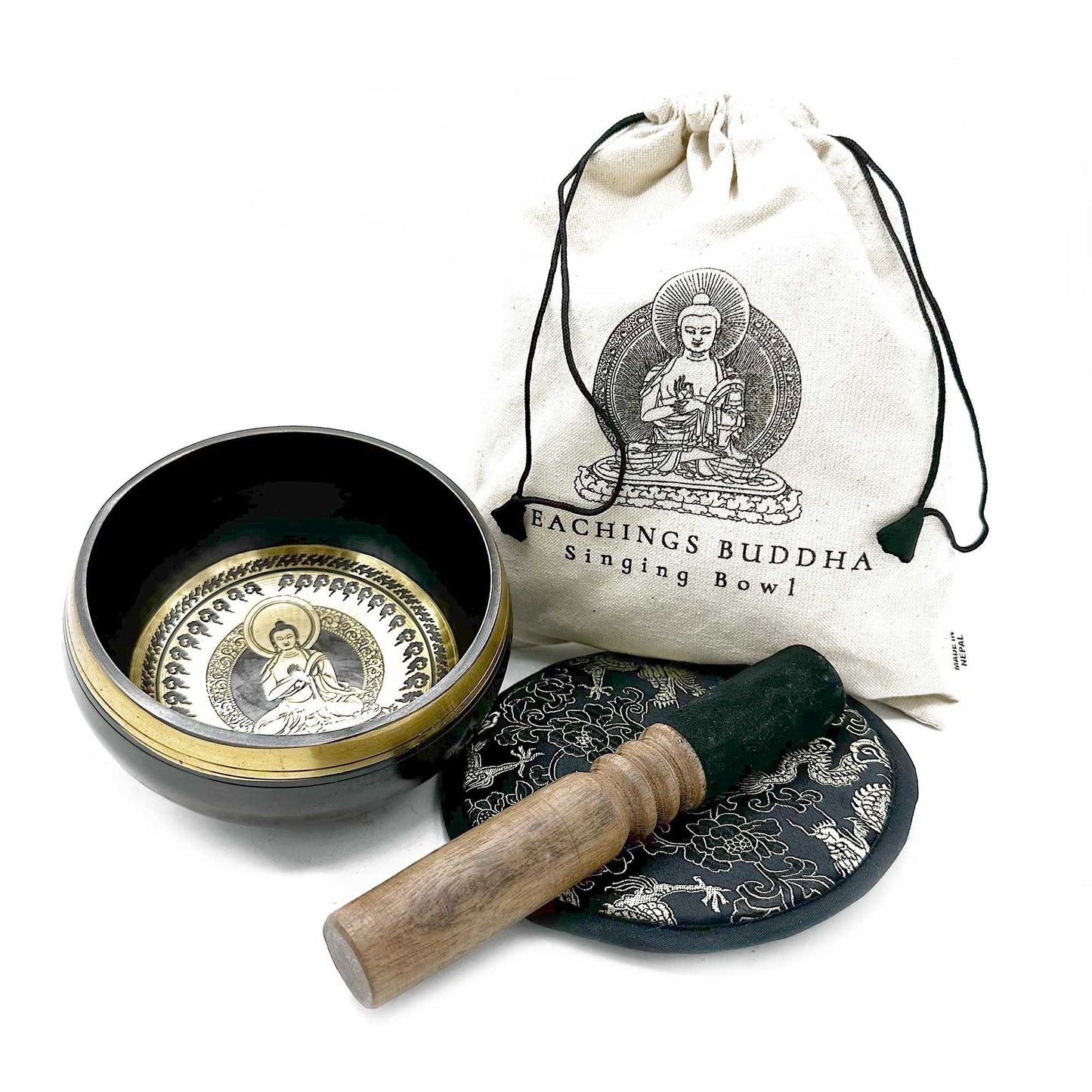 Brass Tibetan singing bowl sits open with a wooden striker on a patterned cushion beside a drawstring canvas bag on a white surface; text on bag: "EACHINGS BUDDHA Singing Bowl" and "MADE IN NEPAL".